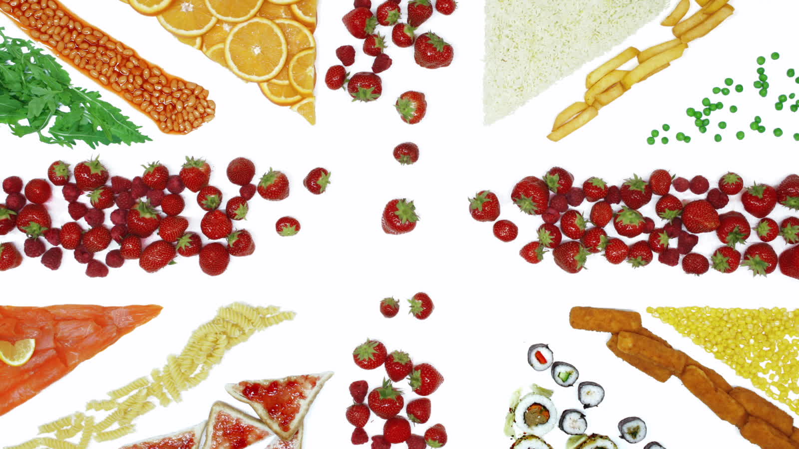 A hand arranging strawberries into the shape of the Union Jack, surrounded by other foods